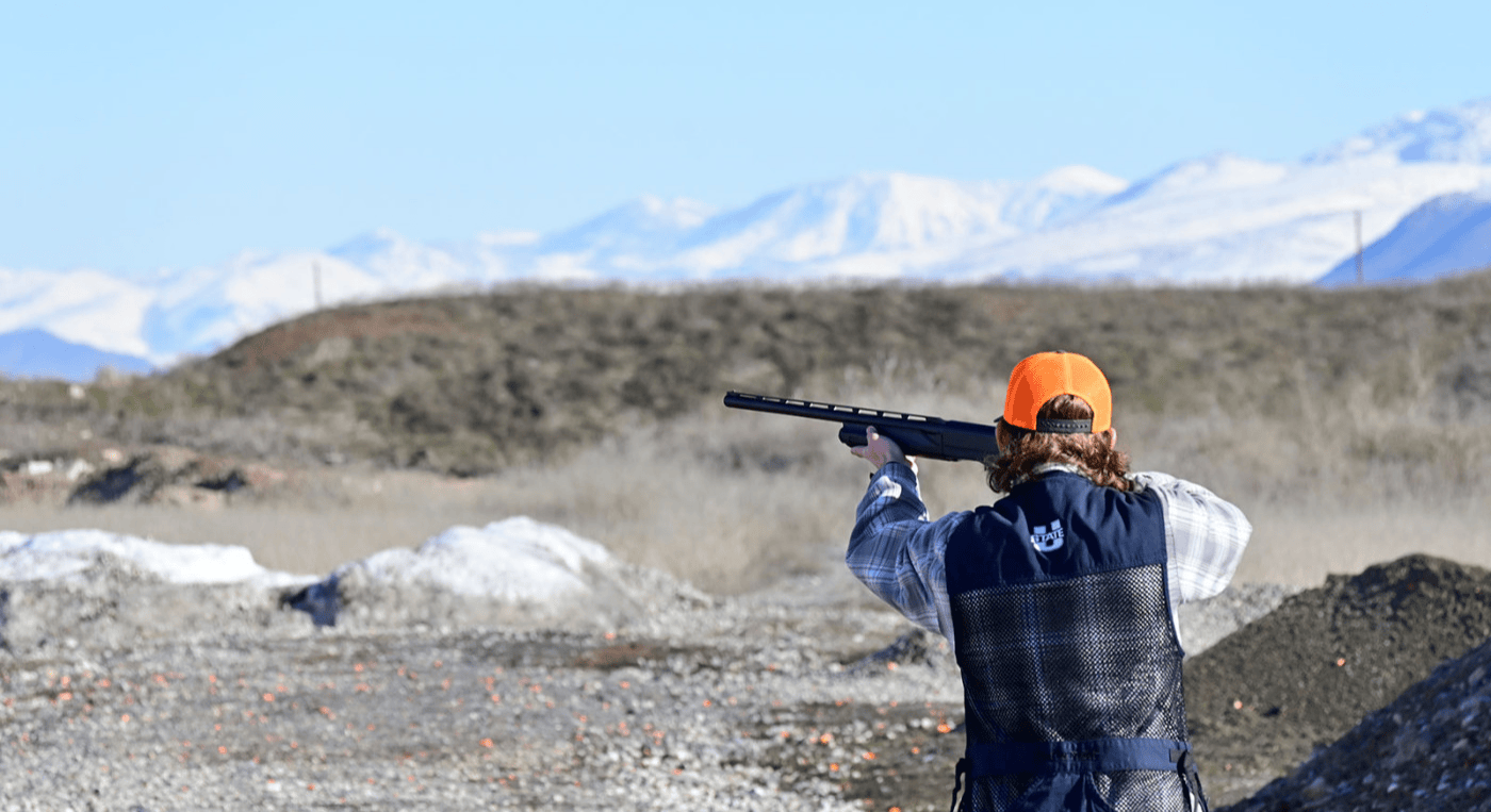 Utah State student aiming a rifle in the desert 